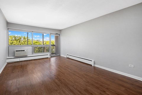 an empty living room with wood floors and a window